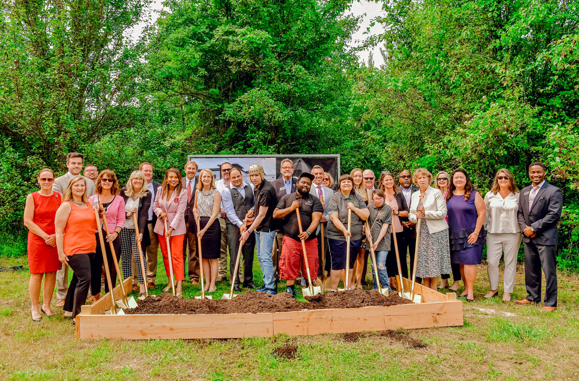 Arc employees, people from the community and elected officials holding shovels to break ground on the site of Port Street Commons