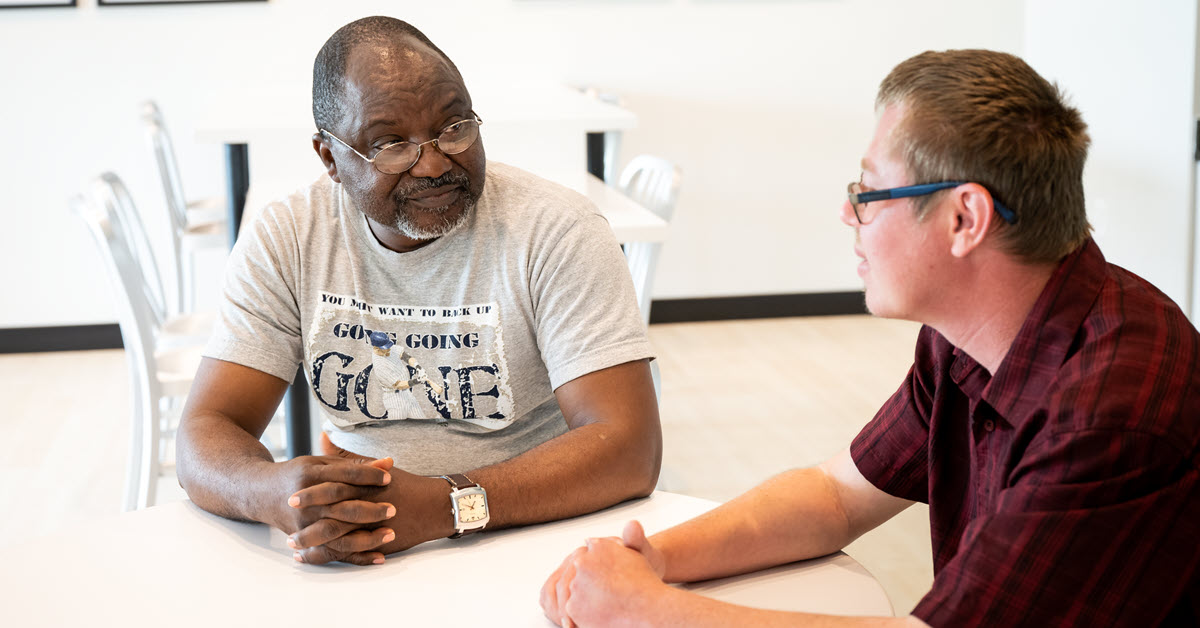 Direct Support Professional sitting at a table with a person he supports