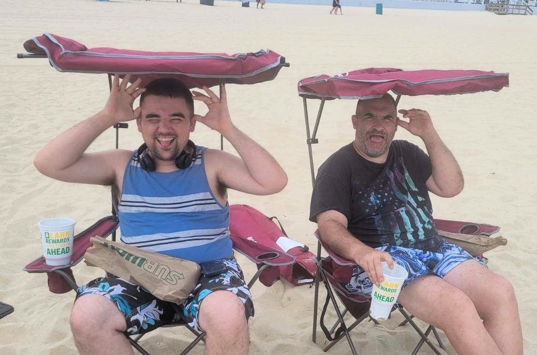 Jonathon and Mike sitting on the beach enjoying their summer vacation