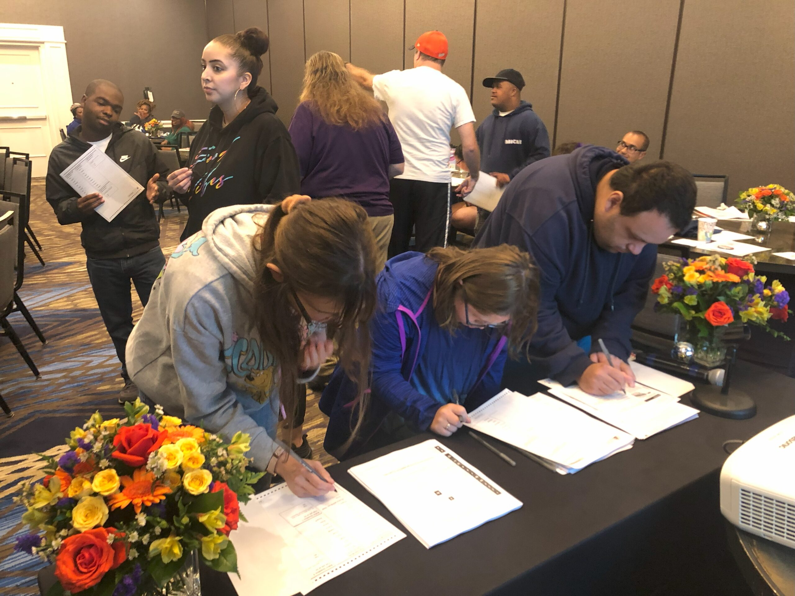 Two people filling out practice voting ballots